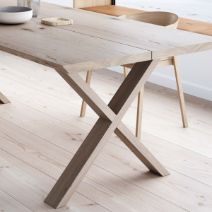 Detaljebillede af et lyst spisebord med træben